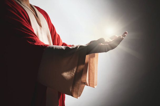 Jesus Christ on grey background, closeup. Miraculous light in hands - Fotó, kép