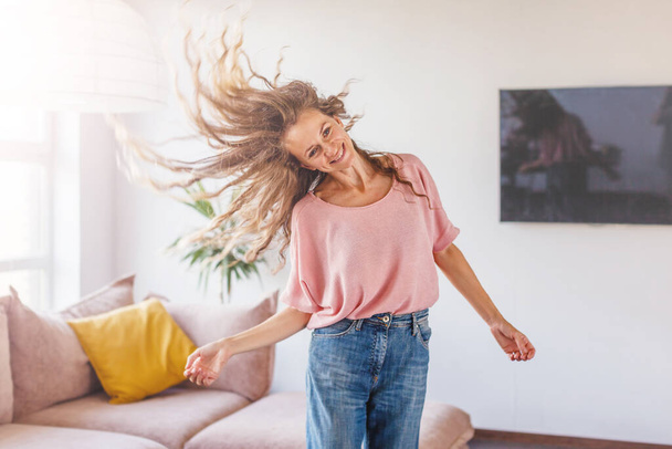 Carefree happy single young attractive woman dancing alone at living room, independent active lady having fun listening music enjoying freedom weekend time lifestyle at home - Fotoğraf, Görsel