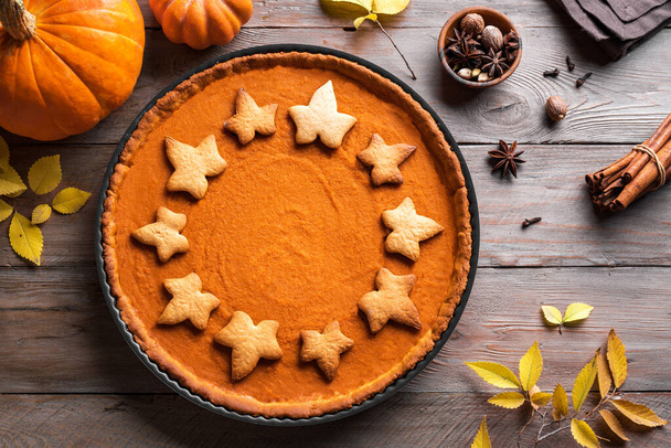 Pumpkin Pie with spices and organic pumpkins on wooden background. Homemade pastry for Thanksgiving holiday - traditional autumn  Pumpkin Pie or tart. - Valokuva, kuva