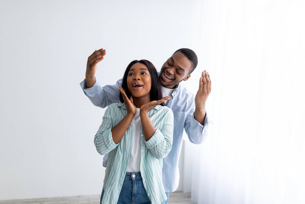 Mudar de casa. Homem negro fazendo surpresa para a esposa e mostrando seu apartamento após a realocação, espaço livre - Foto, Imagem