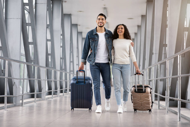 Listo para las vacaciones. Romántica pareja de Oriente Medio caminando con maletas en la terminal del aeropuerto - Foto, Imagen