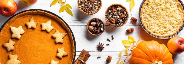 Thanksgiving autumn pies on white wooden background, banner. Fall homemade pumpkin, apple and pecan pies and ingredients for autumn holidays. - Photo, image