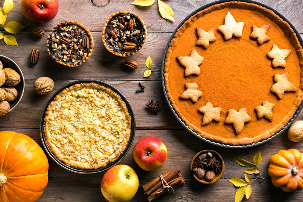 Thanksgiving autumn pies on wooden background. Fall homemade pumpkin, apple and pecan pies and ingredients for autumn holidays. - Photo, image