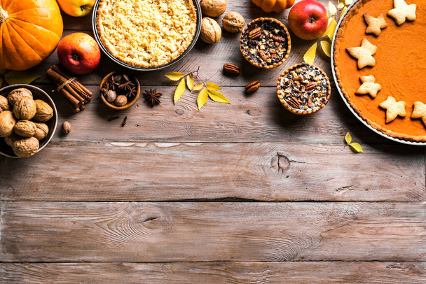 Thanksgiving autumn pies on wooden background, copy space. Fall homemade pumpkin, apple and pecan pies and ingredients for autumn holidays. - 写真・画像