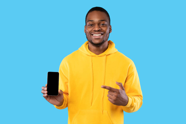 Afričan chlap zobrazující telefon s prázdnou obrazovkou na modrém pozadí - Fotografie, Obrázek