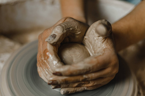 Female hands of potter making cup in traditional style. Hands make dishes from clay - Foto, afbeelding