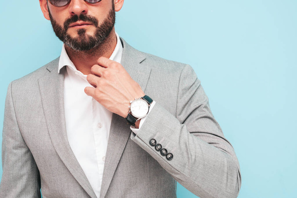 Closeup portrait of handsome confident stylish hipster lambersexual model.Sexy modern man dressed in elegant suit. Fashion male posing in studio near blue wall in sunglasses - Фото, зображення