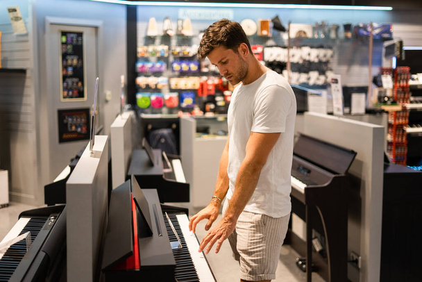 Customer testing electronic piano in store - Photo, image