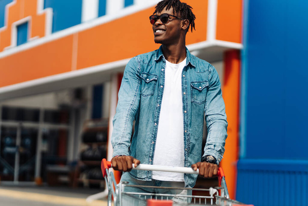 afro american black man with shopping cart in front of mall shopping mall, successful shopping mall - Fotoğraf, Görsel