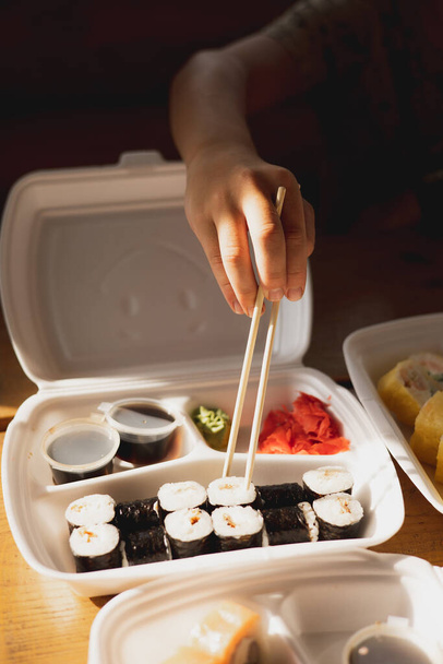 Toimitus sushi rullina muovi ruoka-astiaan. Japanilaista ruokaa. Sushirullia kertakäyttöisissä säiliöissä. Ruoanjakelu- ja noutokonsepti - Valokuva, kuva