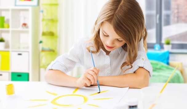 boldog lány ecsettel és színekkel rajz otthon - Fotó, kép