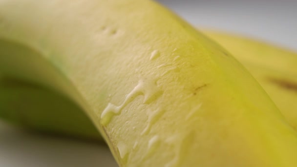 A drop of clear water falls on a ripe yellow banana in slow motion. Macro shot - Felvétel, videó