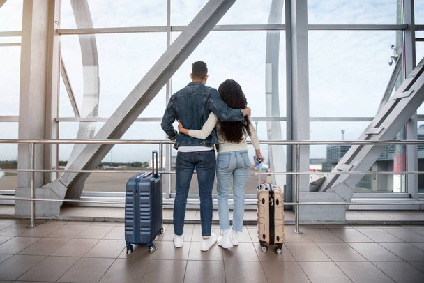 一緒に旅行する。空港ターミナルに立つ若いカップルの後部ビュー - 写真・画像