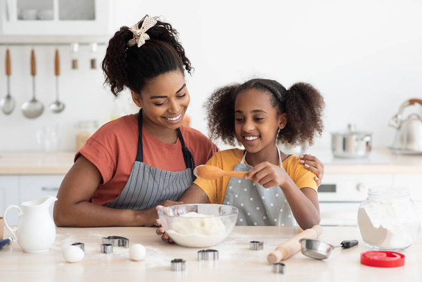 Fekete anya megmutatja a tini lányának, hogyan kell sütit csinálni. - Fotó, kép