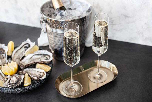 Champagne glasses with sparkling wine and bottle in bucket near oysters - Foto, immagini