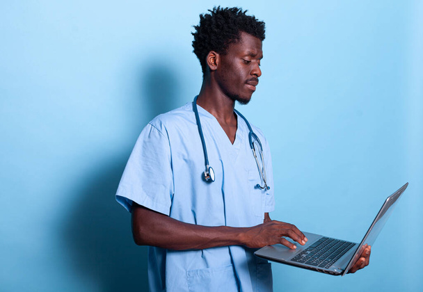 Afrikanische amerikanische Arzthelferin schaut auf Laptop in der Hand - Foto, Bild