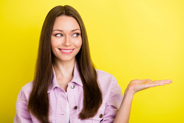 Photo of curious brunette hairdo millennial lady hold empty space wear pink shirt isolated on yellow color background - Φωτογραφία, εικόνα