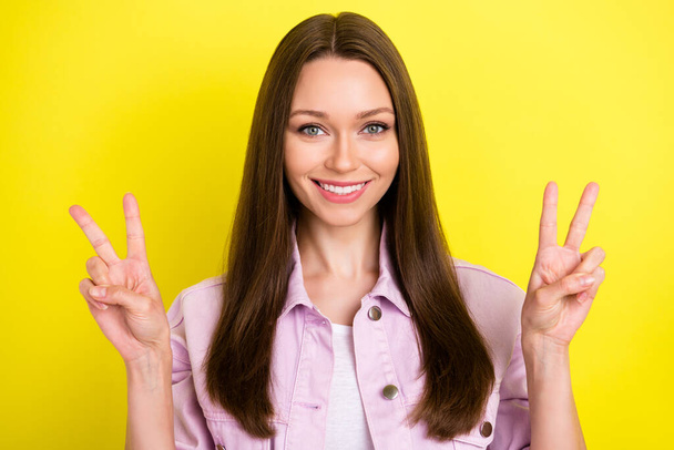 Portrait of attractive cheerful brown-haired girl showing v-sign good mood isolated over bright yellow color background - Fotoğraf, Görsel