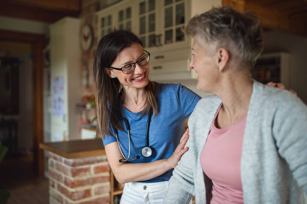 Healthcare worker or caregiver visiting senior woman indoors at home, supporting. - Foto, Imagem