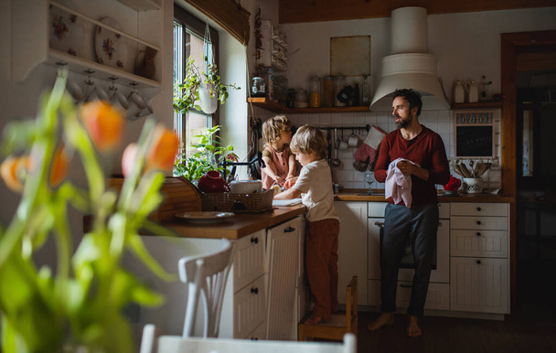 Mature father with two small children washing dishes indoors at home, daily chores concept. - Valokuva, kuva