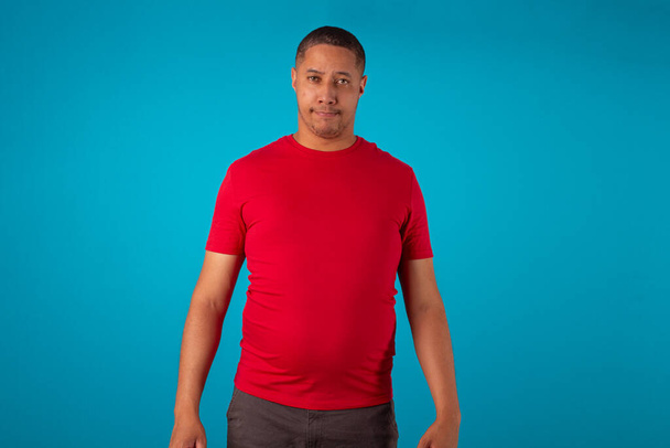 Adulto en camisa roja sobre un fondo azul, haciendo varias expresiones faciales. - Foto, imagen