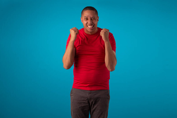 Adult in red shirt on a blue background, making various facial expressions. - Foto, Imagen