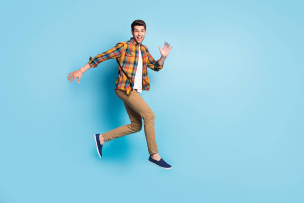 Photo of sweet excited young guy dressed plaid shirt spectacles smiling jumping high isolated blue color background - Foto, Imagen
