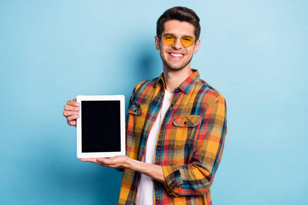 Portrait of attractive cheerful guy holding in hands device ebook copy space isolated over bright blue color background - Fotoğraf, Görsel
