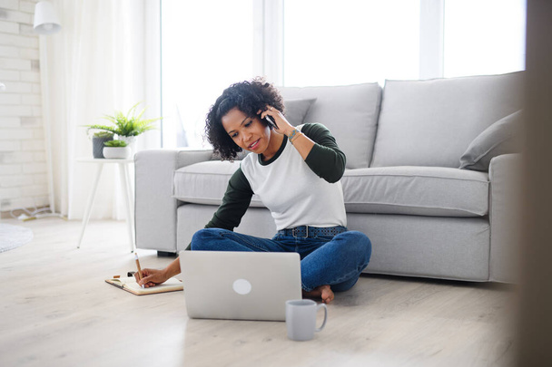 Retrato de mujer madura feliz trabajando en el ordenador portátil y haciendo llamadas telefónicas en el interior, concepto de oficina en casa. - Foto, imagen