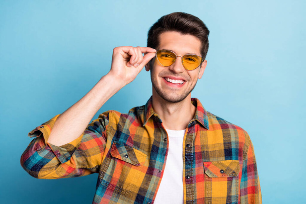 Portrait of attractive toothy cheerful guy touching specs good mood isolated over bright blue color background - Foto, Imagem