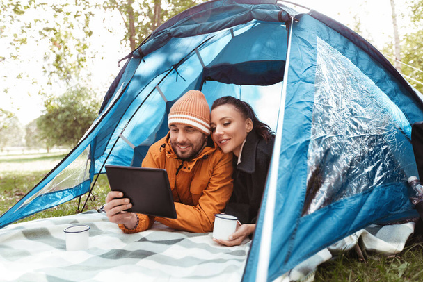 couple with tablet pc drinking tea inside tent - Foto, Imagen