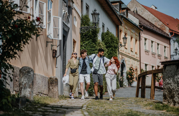 Front view of group of happy young people outdoors on trip in town, walking and talking. - Foto, afbeelding