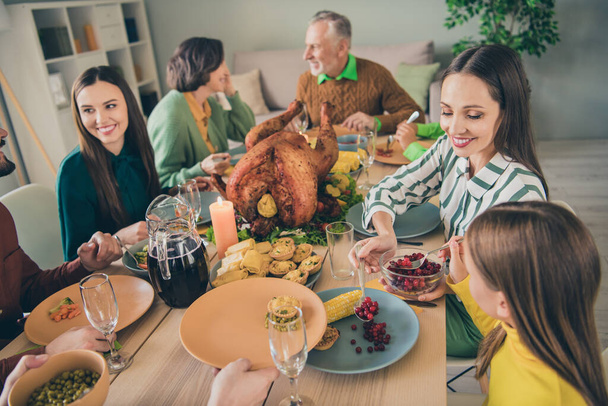 Photo of cute cheerful family eating holiday turkey sitting table smiling communicating indoors house room - Fotó, kép