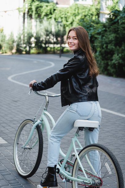 cheerful young woman riding bicycle on urban street of europe  - Foto, Imagem