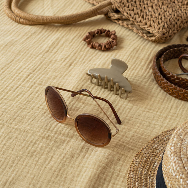 Módní ženské plážové doplňky na žluté mušelínové látce. Pásek, slamák, sluneční brýle, klobouk, sluneční brýle. Estetický luxusní boho koncept pro cestování blog, sociální média - Fotografie, Obrázek