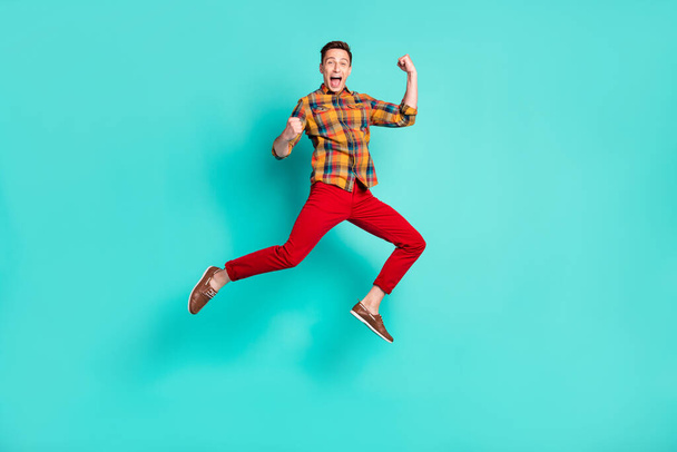 Full body photo of funky brunet millennial guy jump wear shirt turquoise sneakers isolated on teal background - Photo, Image
