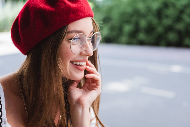 happy young woman in red beret and eyeglasses looking away outside - Φωτογραφία, εικόνα