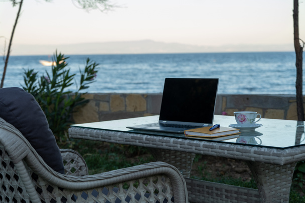 робота з літнього будинку віддалена концепція в пандемії, стіл готовий для роботи з ноутбуком на ручці біля моря
 - Фото, зображення