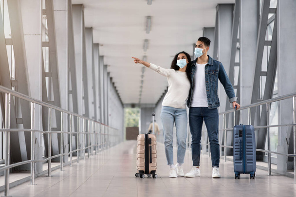 Jeunes conjoints du Moyen-Orient portant des masques médicaux attendant avec des valises à l'aéroport - Photo, image