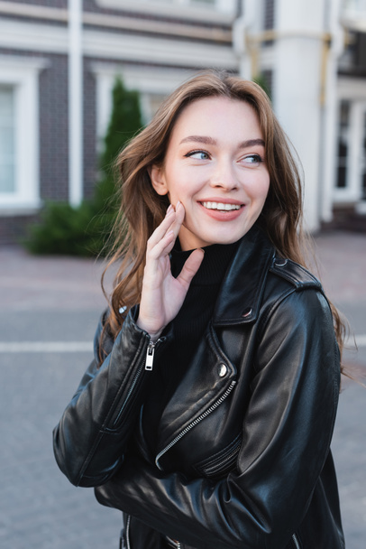 happy young woman in black turtleneck and leather jacket  - 写真・画像