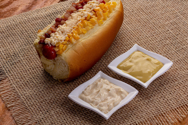 Délicieux hot dog avec des ingrédients et sur fond coloré ou en bois. - Photo, image