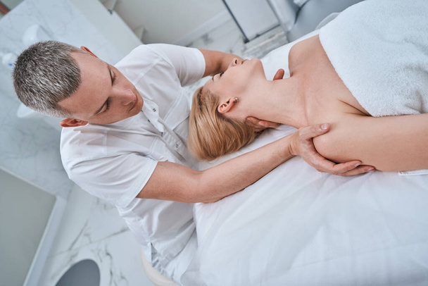 Osteopathic physician treating a young woman for cervicalgia - Foto, afbeelding