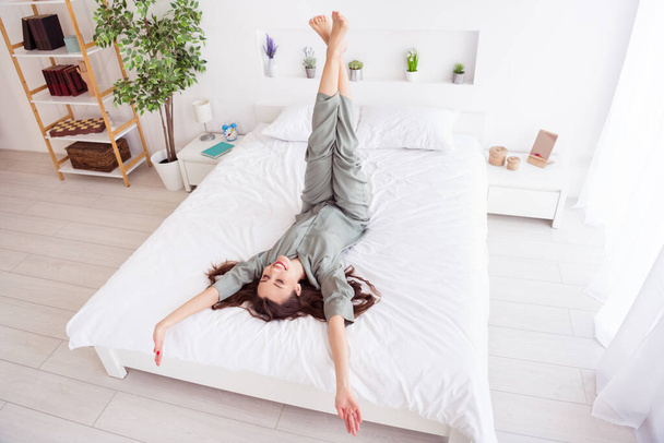 Top above high angle view portrait of attractive dreamy cheerful girl lying on bed at home house light white interior - 写真・画像