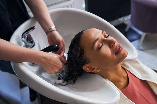 Close up of relaxed woman washing hair in salon - Fotoğraf, Görsel
