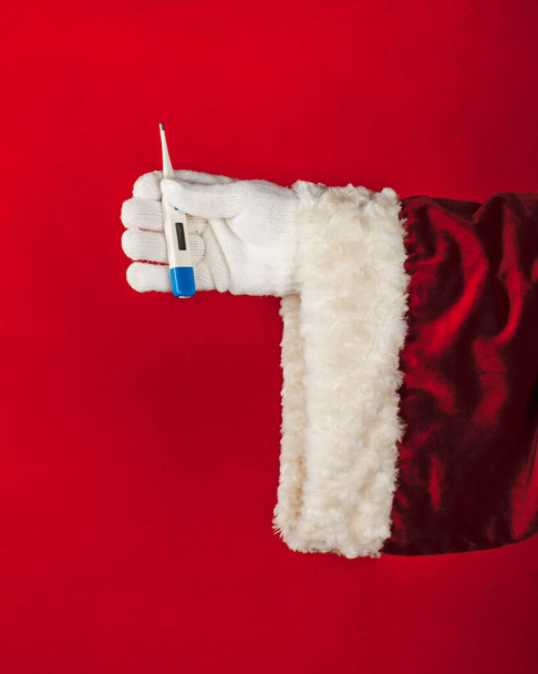 Primo piano mano di Babbo Natale tenendo in mano termometro isolato su sfondo di colore brillante con spazio copia. - Foto, immagini