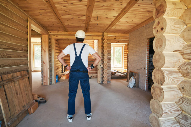 Builder is looking around house under construction - Φωτογραφία, εικόνα