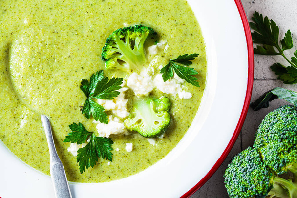 Broccoli soup puree with feta cheese in white plate, close-up. Cooking healthy food concept. - Fotoğraf, Görsel