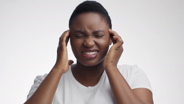 Ataque de migraña. Joven mujer afroamericana estresada sufriendo de dolor de cabeza agudo, masajeando sus sienes - Imágenes, Vídeo