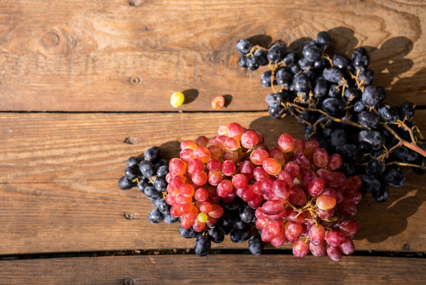 Grapes on a wooden table. Fresh branch of red grapes with leaves. High quality photo - Photo, Image