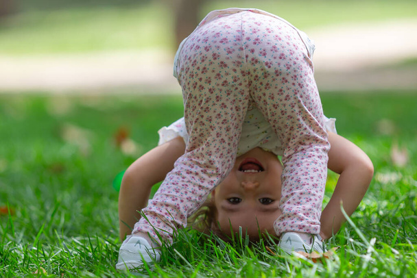Маленькая девочка делает колесики в парке. Детские игры. Outdoo - Фото, изображение